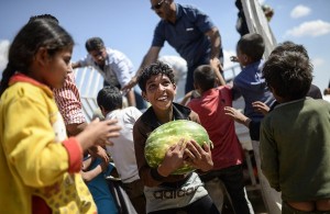 A Syrian child holds a watermelon after they were distibuted near the Akcakale crossing gate between Turkey and Syria at Akcakale in Sanliurfa province on June 16, 2015.  Some 23,000 people have fled from Syria to Turkey between June 3 and 15, the UN refugee agency said. "New fighting in northern Syria has seen 23,135 refugees fleeing across the border into Turkey's Sanliurfa province," during that period, spokesman William Spindler said, citing figures given by Turkish authorities.  AFP PHOTO / BULENT KILIC        (Photo credit should read BULENT KILIC/AFP/Getty Images)