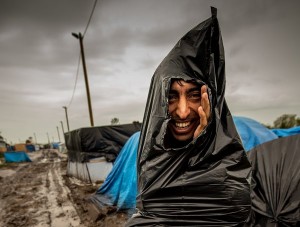 A migrant, who protects himself from the rain with a plastic trash bag, walks through a mudpath of the "New Jungle" migrant camp in Calais, where thousands of migrants live in the hope of crossing the Channel to Britain, on October 21, 2015. European Commission chief Jean-Claude Juncker has called a mini-summit in Brussels on October 25 to tackle the migrant crisis along the western Balkans route, his office said. AFP PHOTO / PHILIPPE HUGUEN        (Photo credit should read PHILIPPE HUGUEN/AFP/Getty Images)
