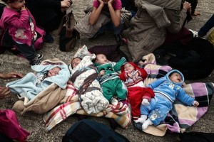 A Syrian family with two-and-a-half-month-old triplets and their relatives with more babies wait for transportation after disembarking with other migrants and asylum seekers from two government-chartered ferries at the Greek port of Piraeus, about 12 kilometres (7 miles) from central Athens, on October 21, 2015. Some 5000 refugees and migrants arrived to the port of Piraeus by government chartered ferries from the islands of Lesbos and Chios. AFP PHOTO / LOUISA GOULIAMAKI        (Photo credit should read LOUISA GOULIAMAKI/AFP/Getty Images)