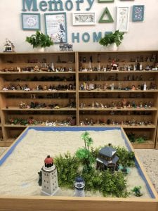 Picture of a sand table and two bookshelves full of miniature figurines