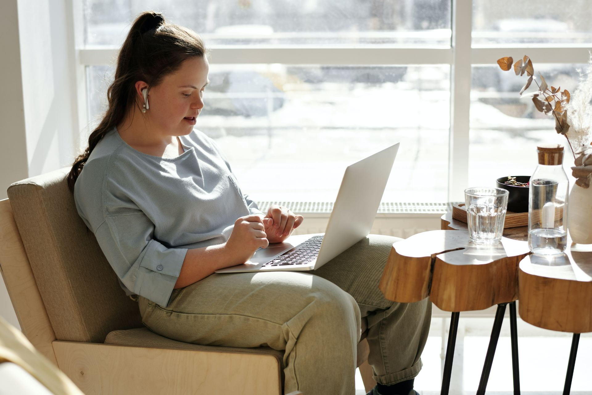 Female sitting at a laptop with earbuds in.
